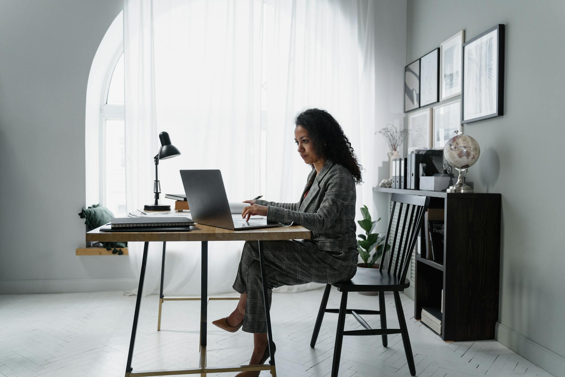 woman in gray jacket sitting on chair using laptop computer